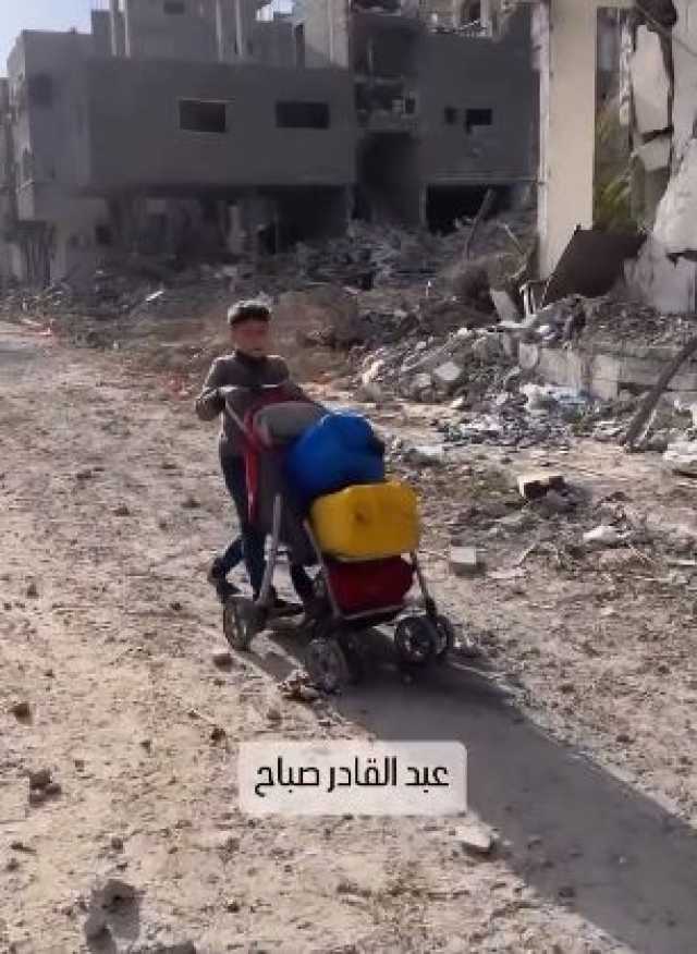 طفل فى غزة يتحمل عبء جلب المياه لأسرته وسط ركام المنازل