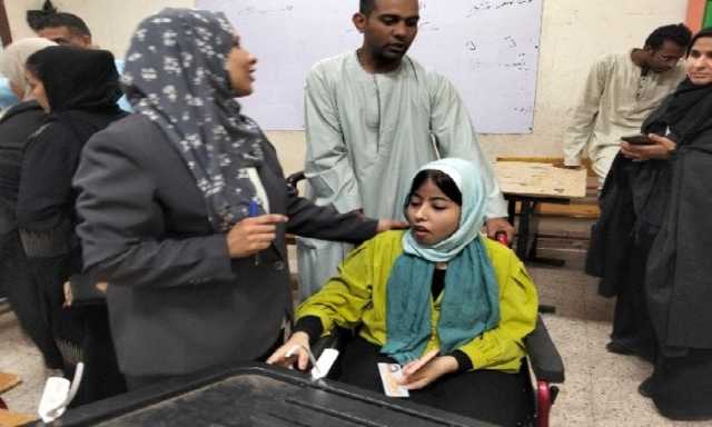 رئيس لجنة انتخابية تساعد مواطنة من ذوي الهمم للادلاء بصوتها في انتخابات الشيوخ بالأقصر