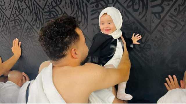 صورة مؤثرة لطفلة رضيعة تبتسم لوالدها أثناء لمسها الكعبة الشريفة